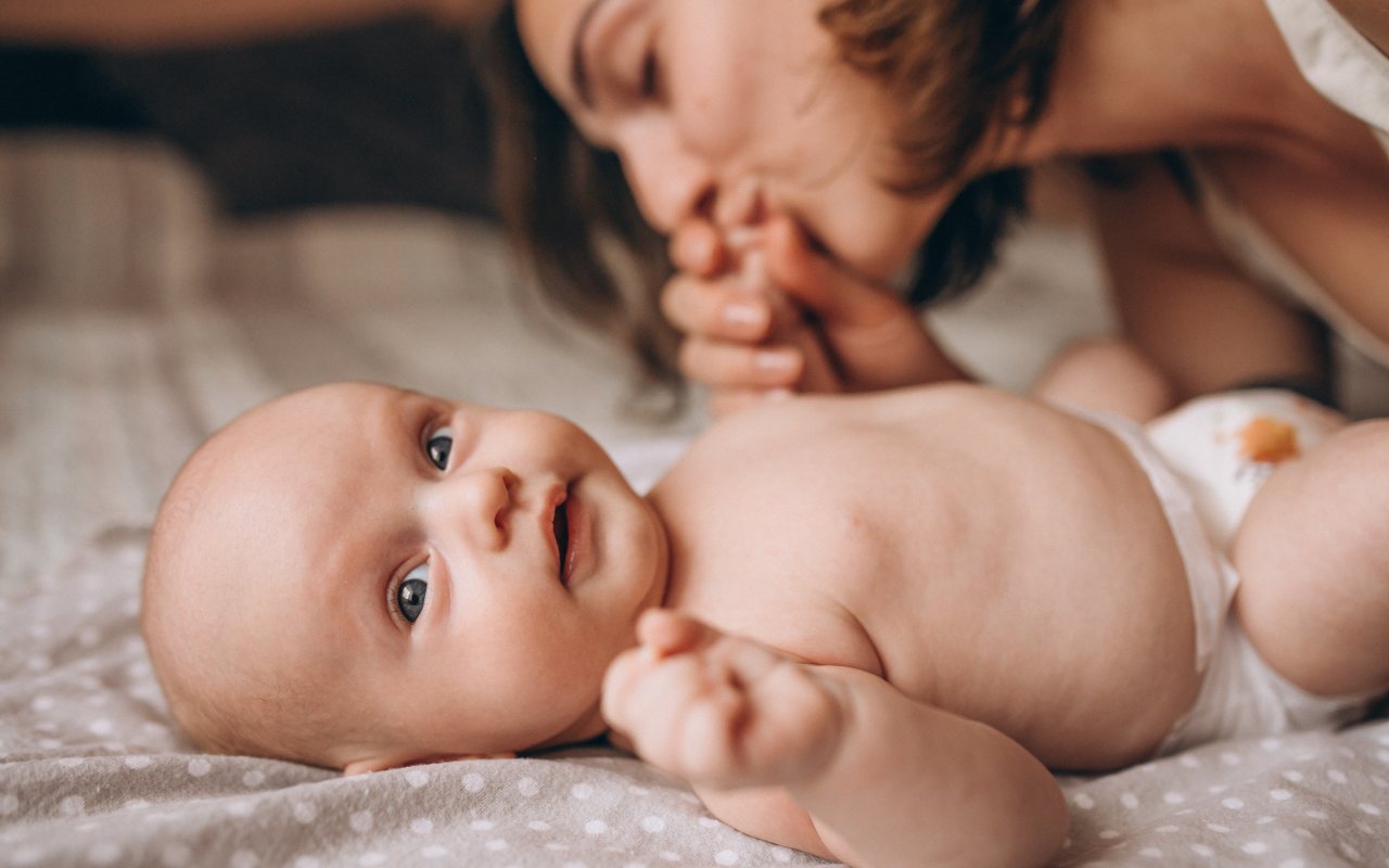 mama ljubi bebu na krevetu